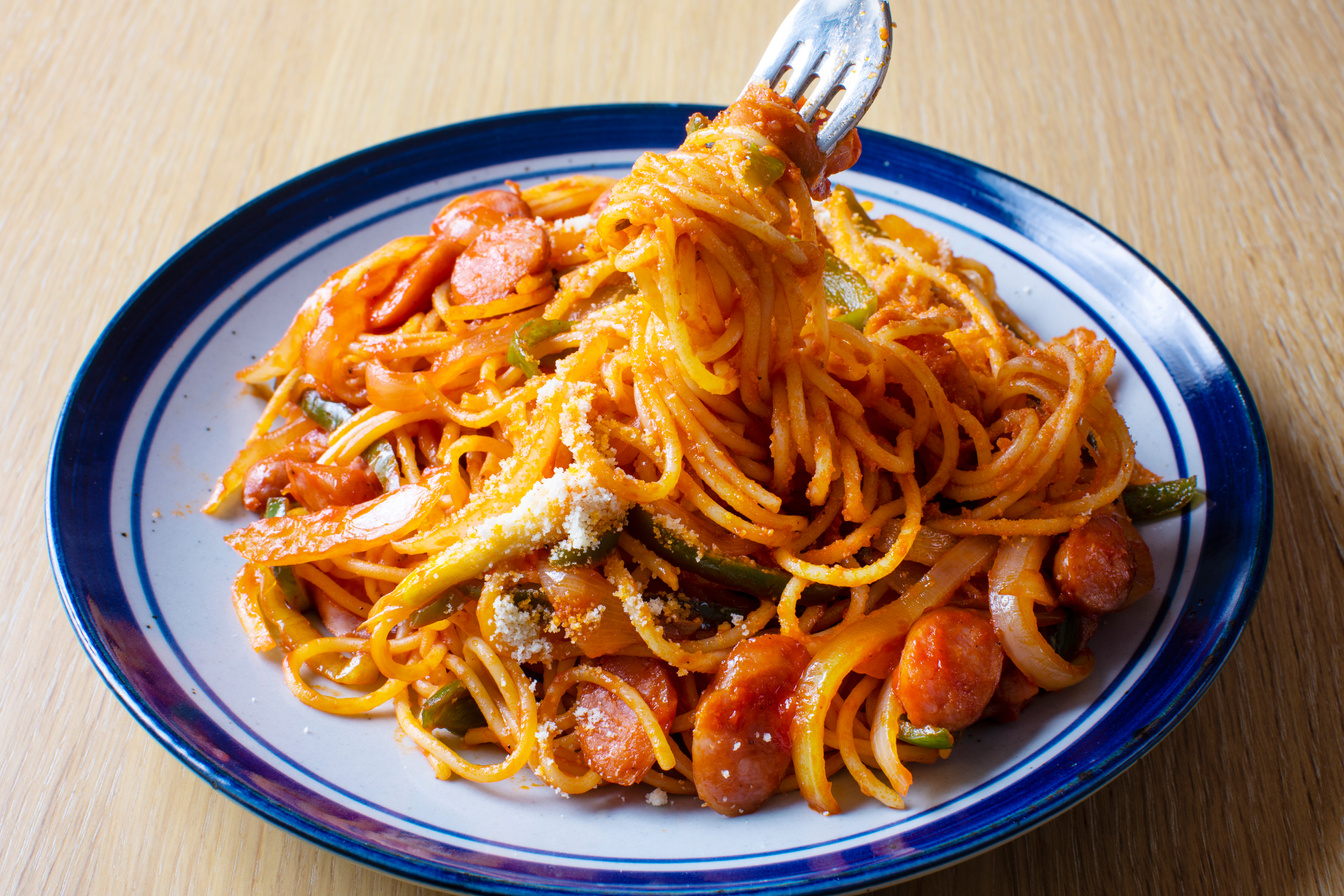 Japanese pasta dish, spaghetti (Naporitan) recipe. Naporitan on a plate is placed on a light wood grain table. Spaghetti with fork Entangled.